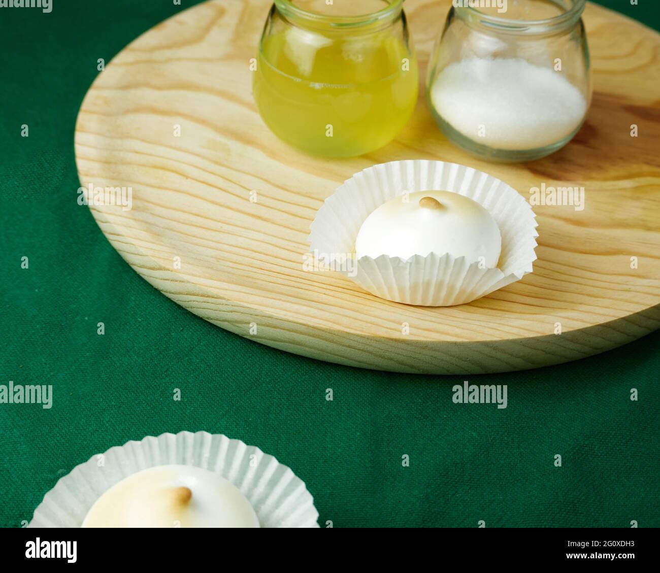 Plusieurs desserts français meringue sous forme de silicone moules sur nappe verte et ses ingrédients sur une assiette ronde en bois Banque D'Images