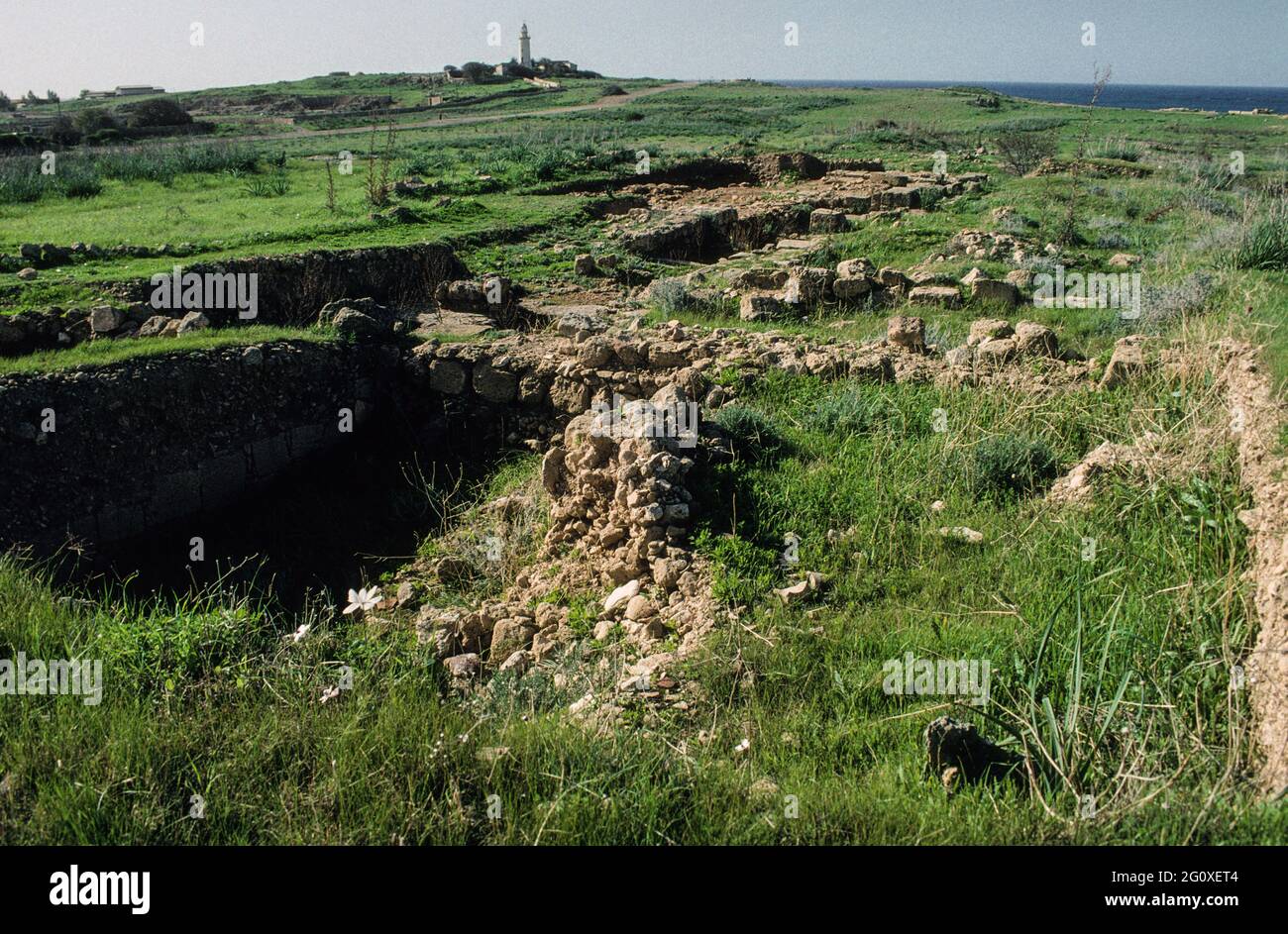Murs de fondation inexplorés des temps anciens près des célèbres Tombeaux des rois près de Paphos. En arrière-plan le phare de Paphos. Banque D'Images