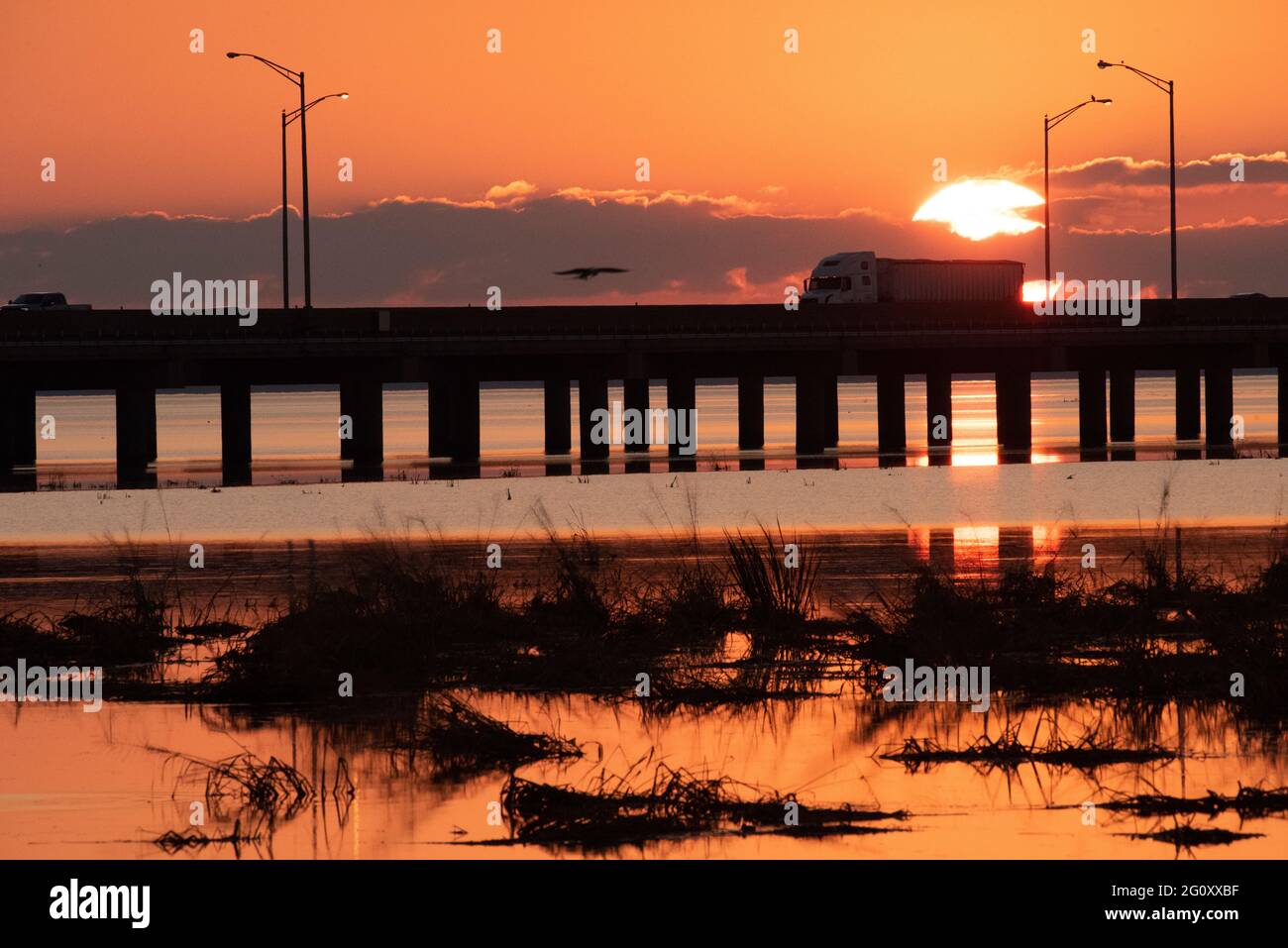 Un semi-tracteur-remorque traverse Mobile Bay en Alabama au coucher du soleil le 26 octobre 2020. Banque D'Images