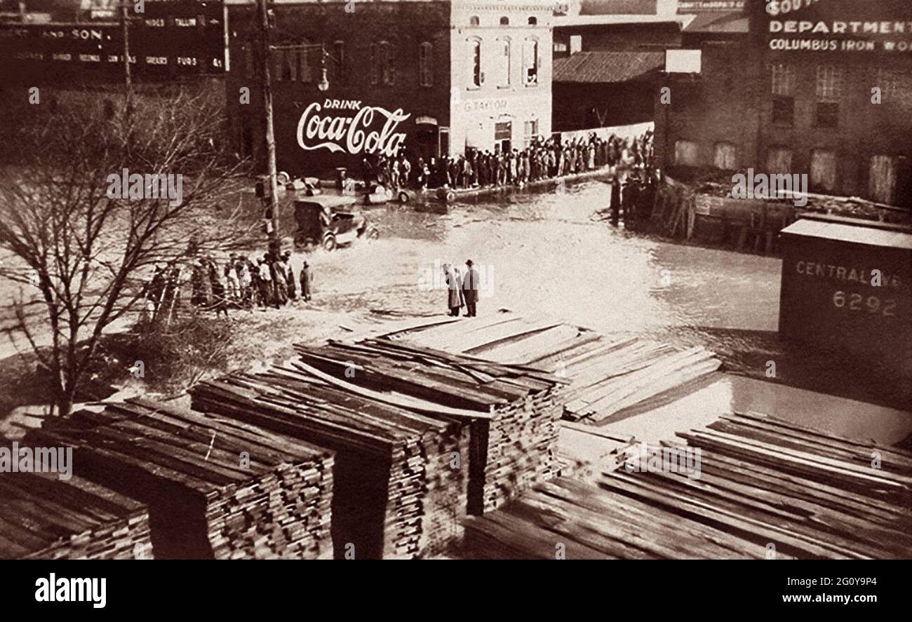 Une voiture d'époque traverse les rues inondées de Columbus, en Géorgie, tandis que les spectateurs regardent depuis un sol sec. La rivière Chattahoochee, qui longe le centre-ville de Columbus, a débordé ses berges à la mi-février 1900. Banque D'Images