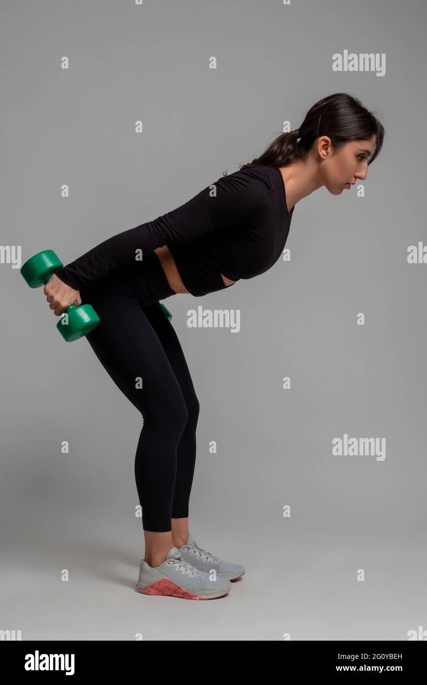 Fille sportive effectuant des triceps kick back avec des haltères sur fond  gris Photo Stock - Alamy