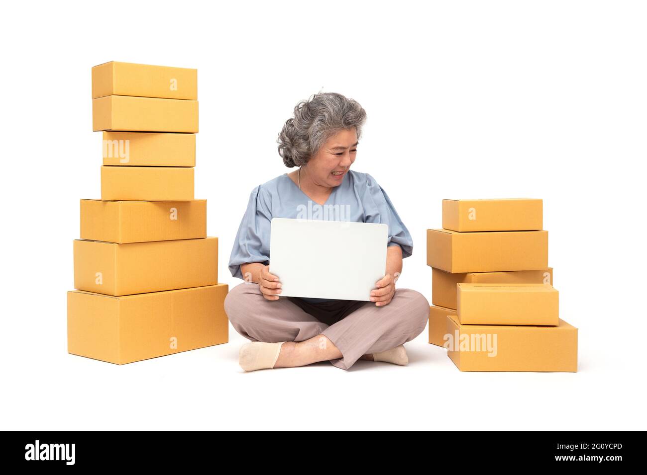 Femme asiatique senior démarrage petite entreprise freelance avec boîte à colis et ordinateur portable et assis sur le sol isolé sur fond blanc, marque en ligne Banque D'Images