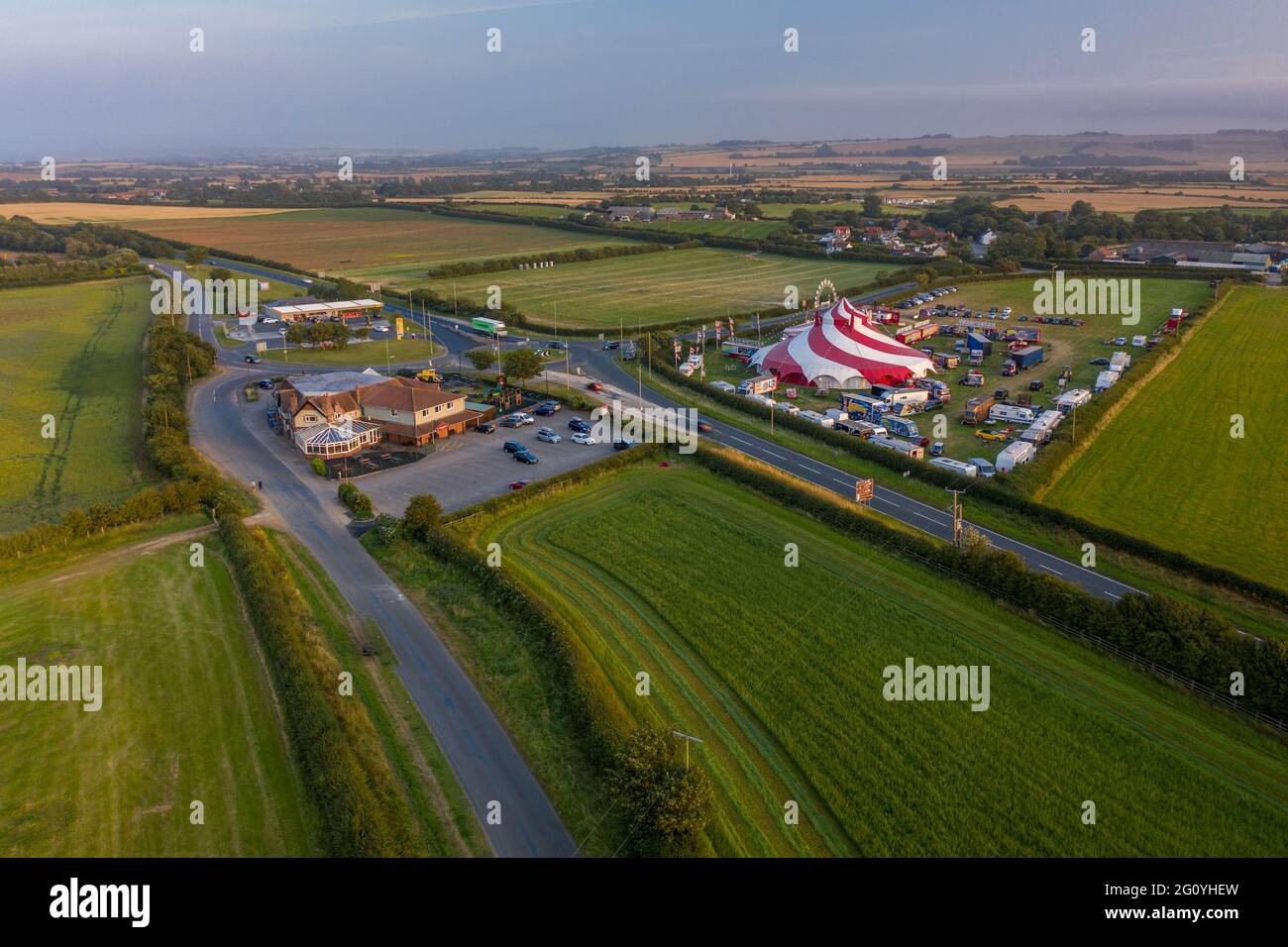 Un fermier a tendance à son champ dans un tracteur tandis qu'un cirque s'installe à côté du Blue Dolphin Holiday Park et du Plow Pub Aerial Images Drone Air Filey Banque D'Images