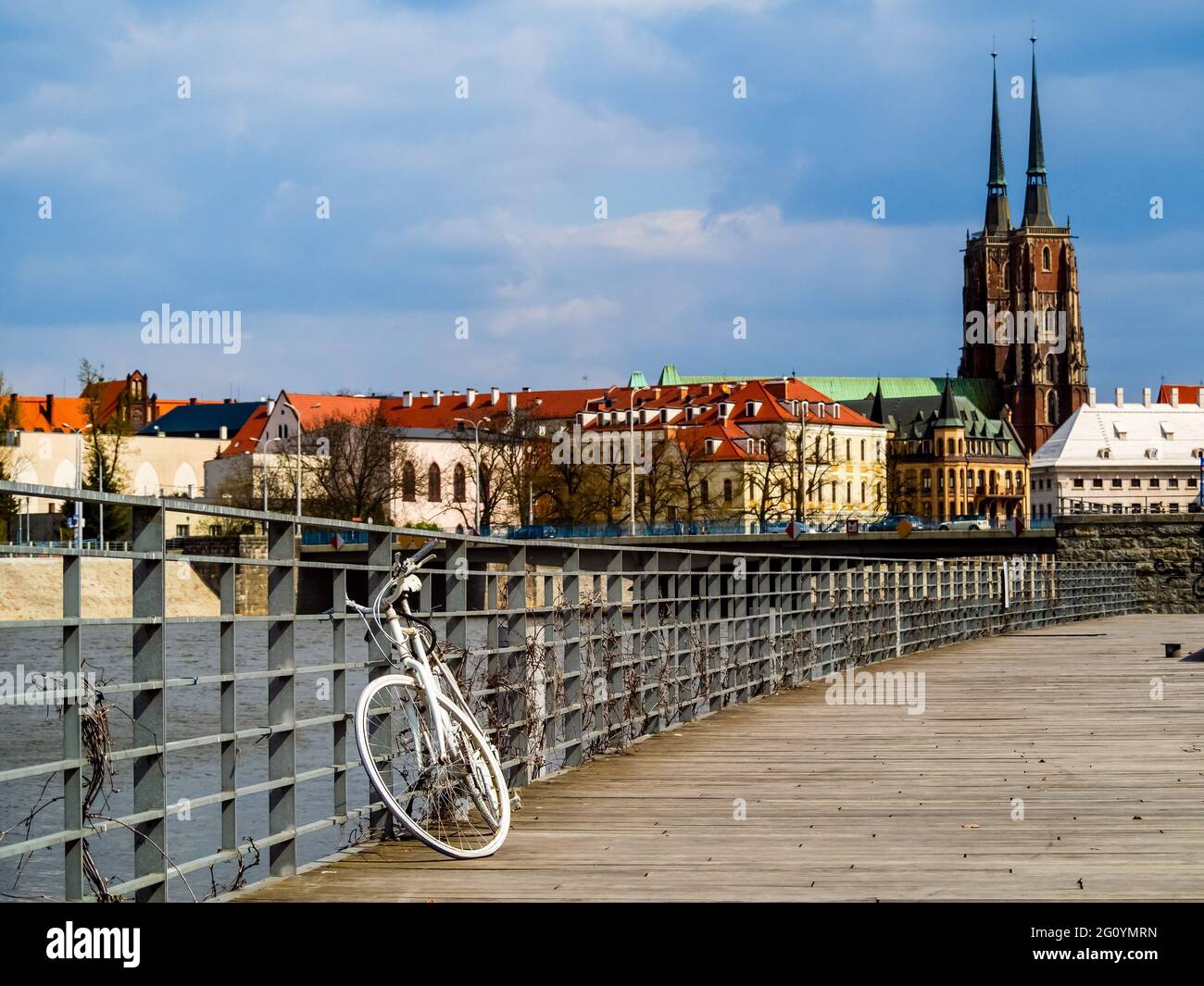 Vélo rétro blanc abandonné sur la jetée en bois de la ville avec vue sur la vieille ville. Wroclaw, Pologne Banque D'Images