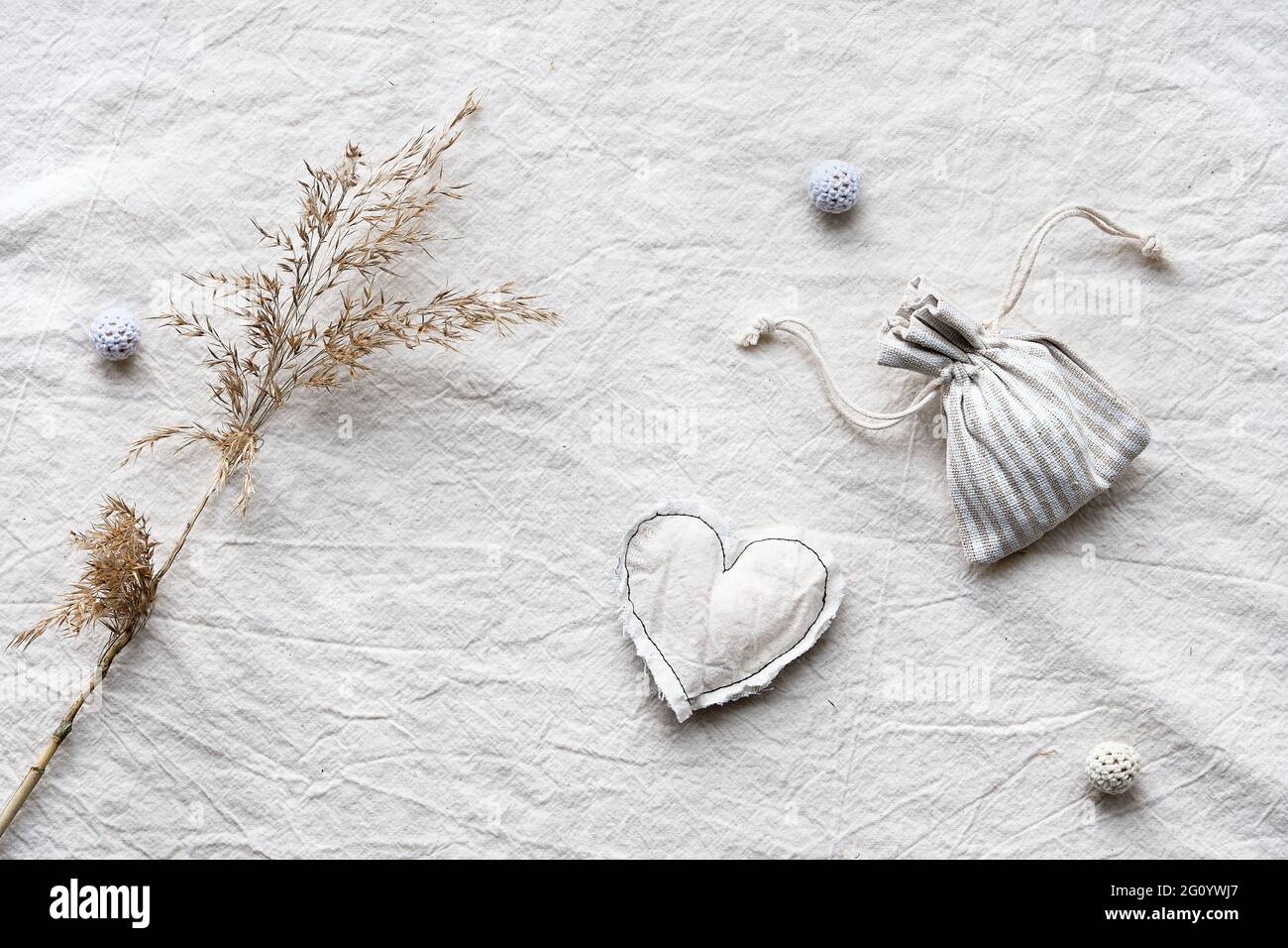 Toile à plat avec roseaux secs, pampas d'herbe, coeur doux et sac en coton avec herbes parfumées sèches. Sur fond de nappe blanc avec fabrication artisanale Banque D'Images