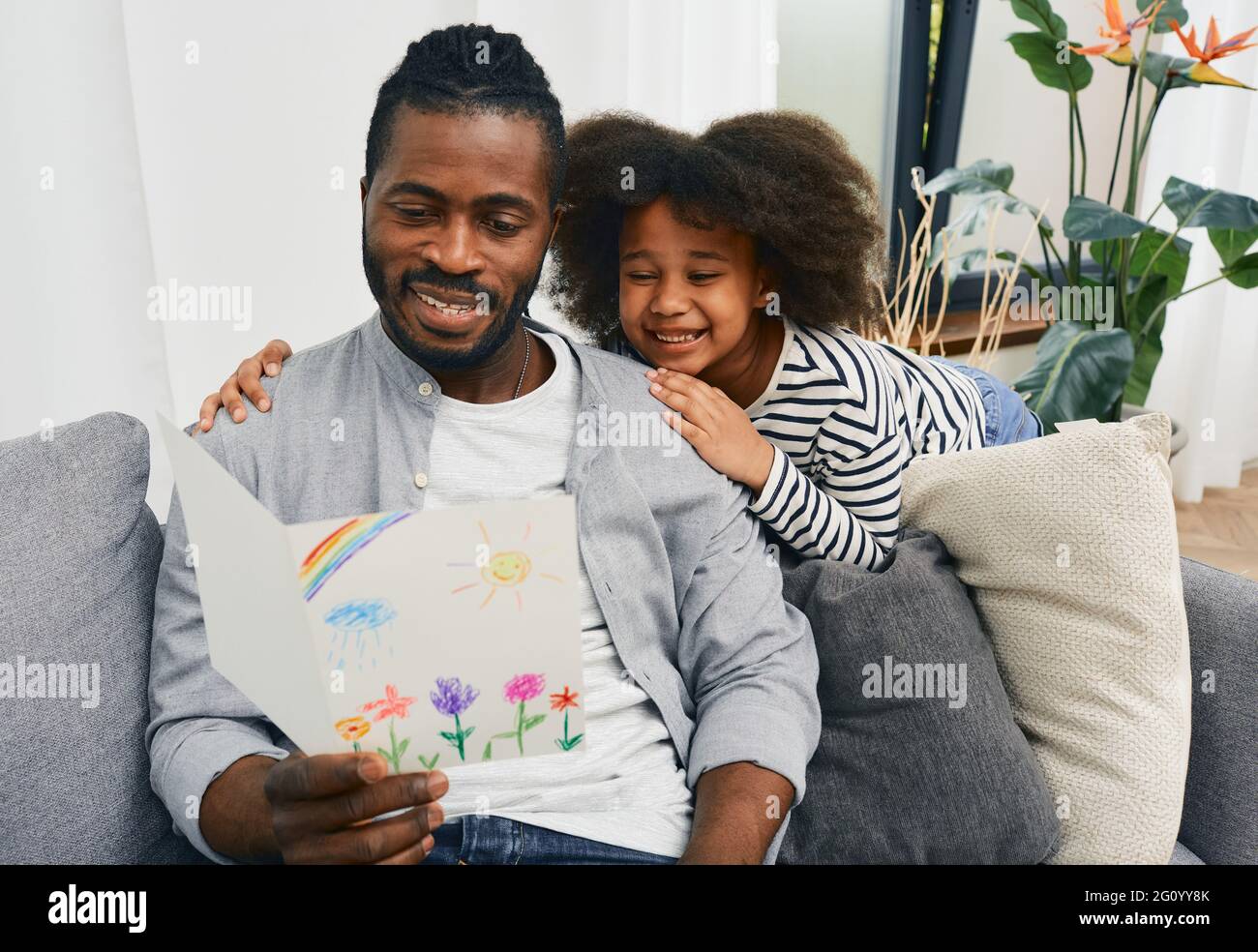 Fête des pères. La fille afro-américaine donne à papa une carte de vœux qu'elle s'est attidée et qu'elle l'embrasse chez elle Banque D'Images