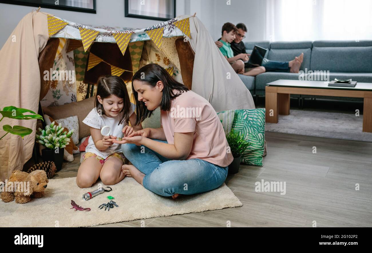 Mère et fille jouant pendant que le père et le fils utilisent un ordinateur portable Banque D'Images