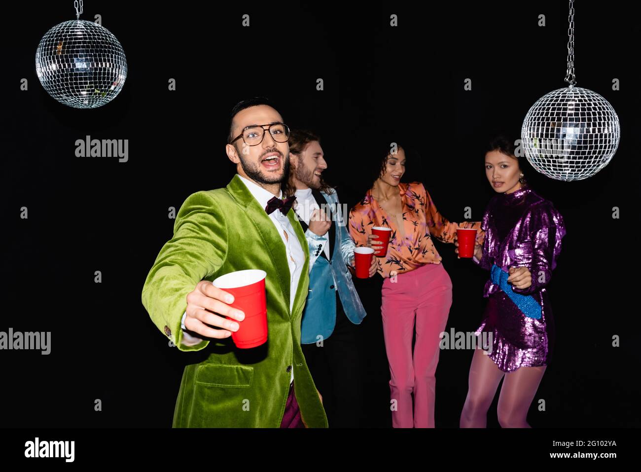 homme arabe positif en lunettes dansant avec des amis multiraciaux dans des  vêtements colorés en boîte de nuit sur fond noir Photo Stock - Alamy