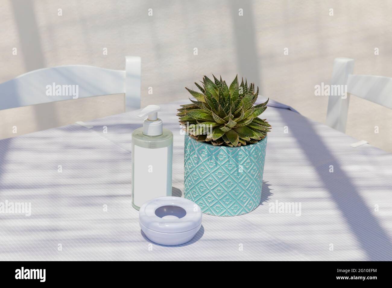 Tableau pour deux. Isolé. Copier l'espace. Table dehors au soleil avec un petit cactus , une bouteille aseptisante et un cendrier . Image de stock. Banque D'Images