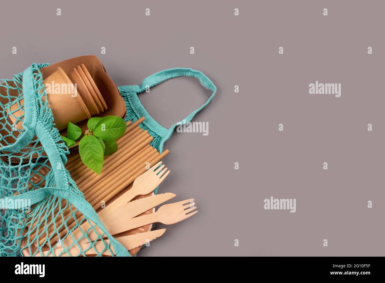 Vaisselle écologique : tasses et récipients en papier kraft avec couverts en bois dans un sac en coton bleu sur fond gris avec espace pour les copies. Rue Banque D'Images