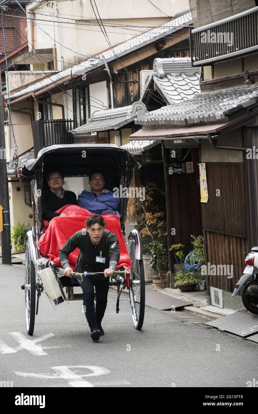 KYOTO, JAPON - 16 décembre 2019 : Kyoto, Japon - 27 novembre 2019 : jinrikisha conduit par un chauffeur non identifié transportant deux touristes à Kyoto. Banque D'Images