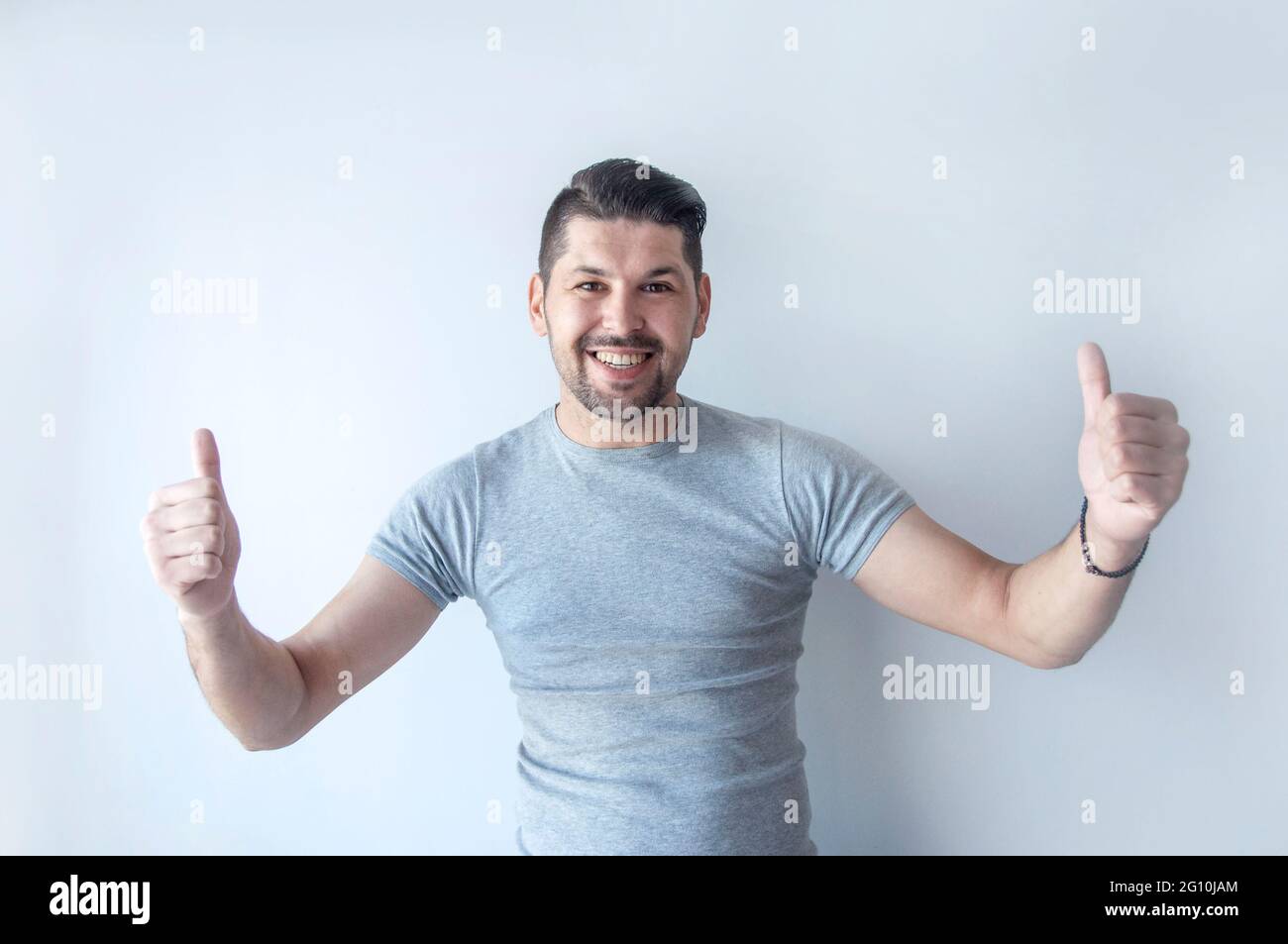 Joyeux jeune homme caucasien dans un t-shirt gris fait un pouce vers le haut signe montrant son soutien, respect et recommandé pour quelqu'un. Langue du corps. I l Banque D'Images