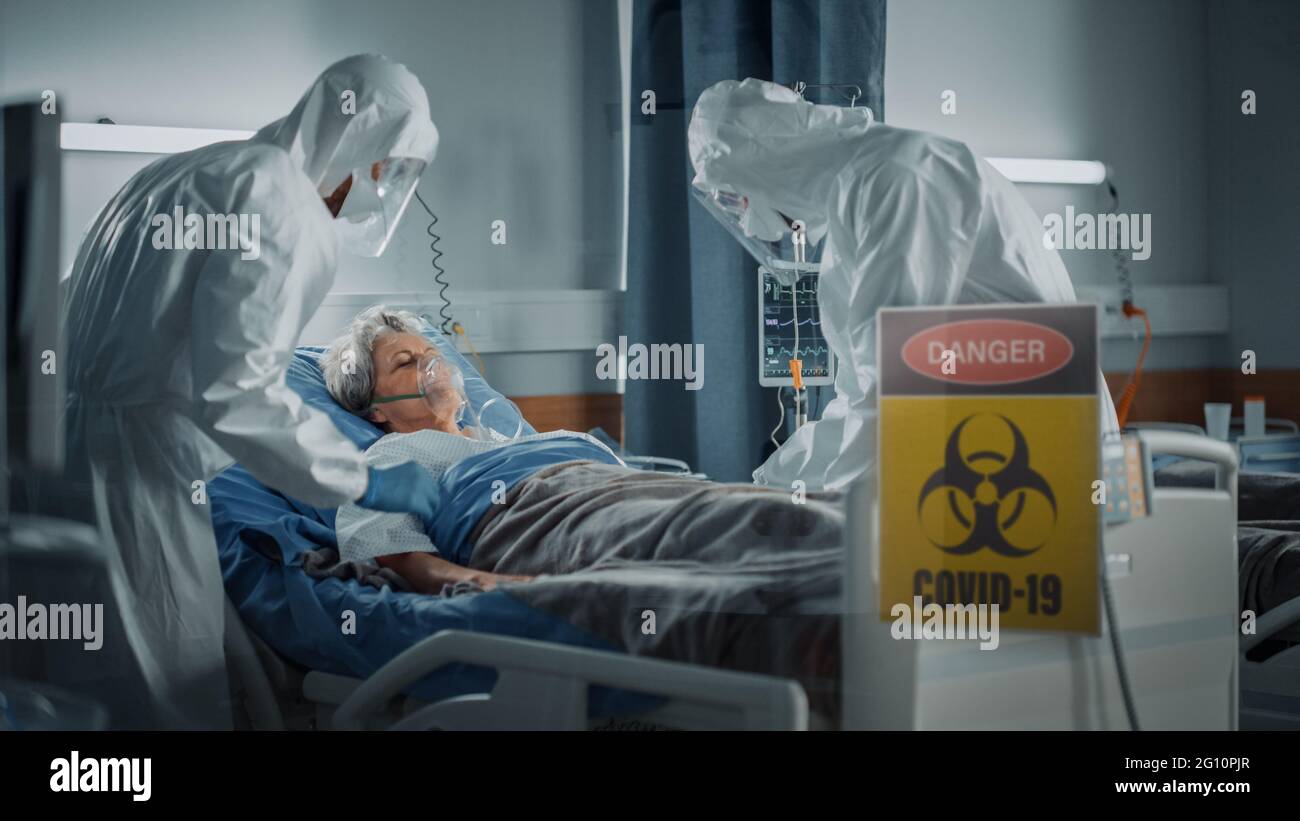 Hôpital coronavirus Service d'urgence quartier: Médecins portant des combinaisons, masques de visage sauver la vie d'un patient senior couché dans le lit, mettre masque d'oxygène et Banque D'Images