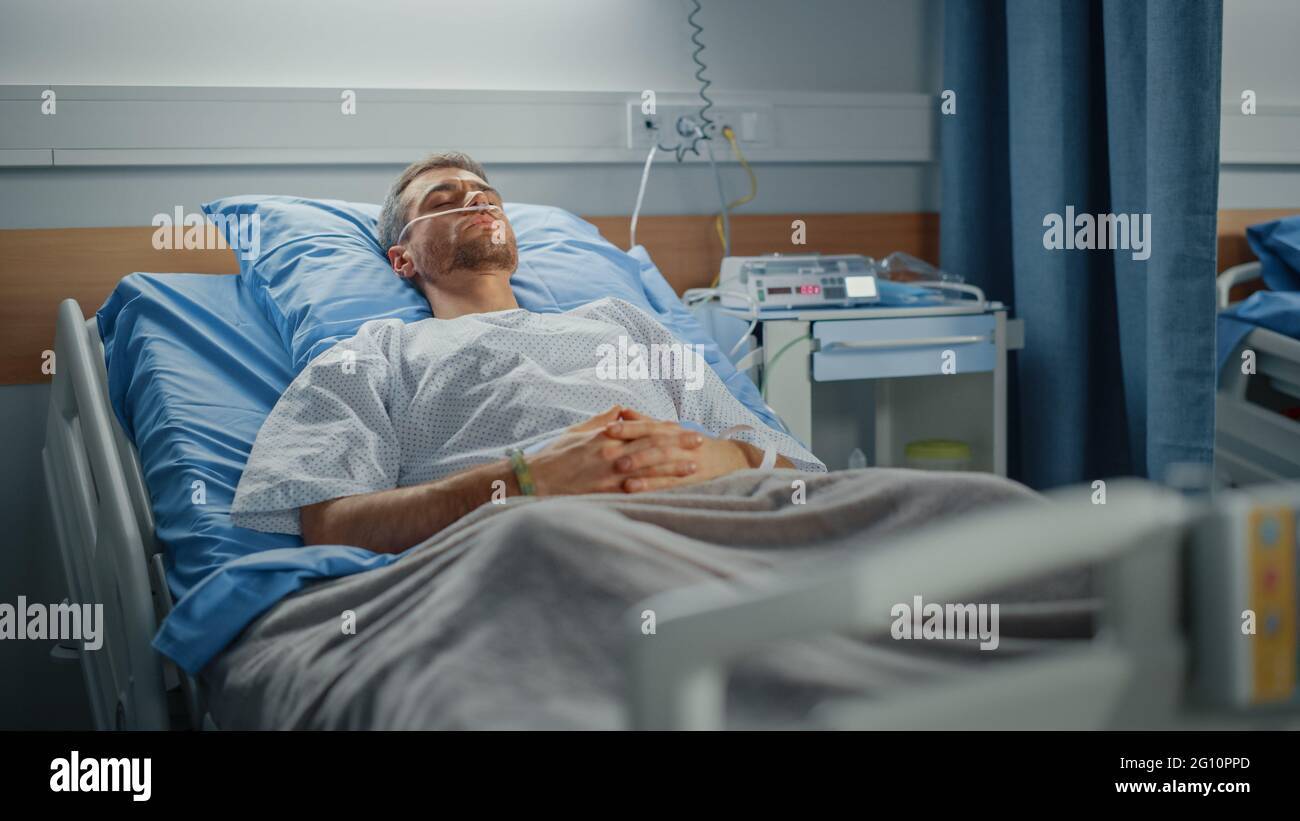 Hôpital: Portrait d'un jeune homme beau portant une canule nasale dormant dans le lit, se rétablissant complètement après la maladie. Un patient de sexe masculin rêvait de lui Banque D'Images