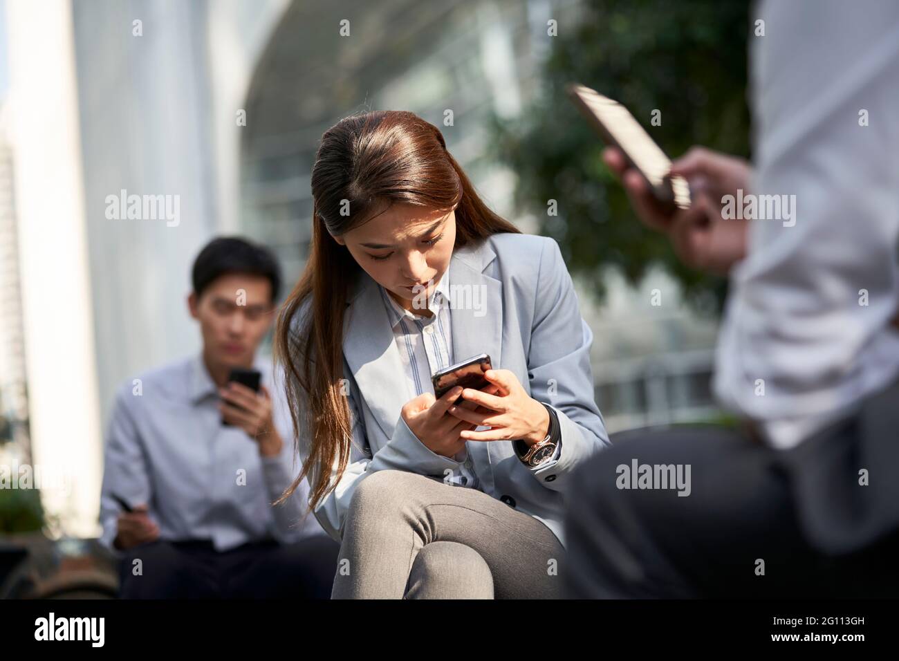 les gens d'affaires asiatiques utilisant le téléphone cellulaire en plein air concept pour la dépendance aux médias sociaux Banque D'Images