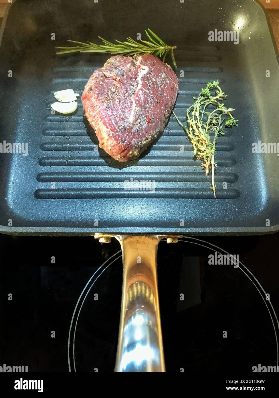 Steak de bœuf aux herbes et à l'ail dans une poêle à grillades Banque D'Images