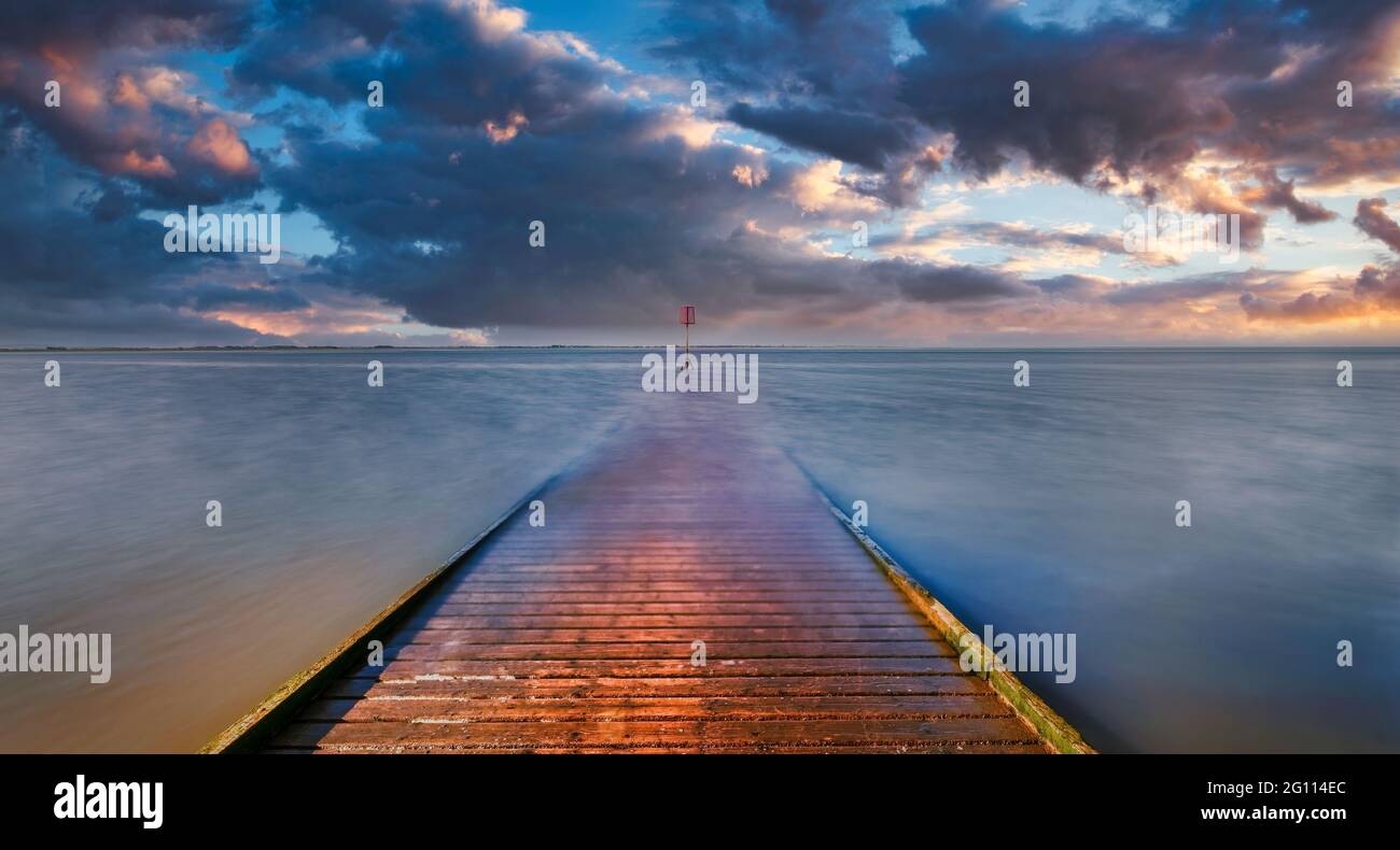 La jetée en bois de Lytham, dans le Lancashire, au Royaume-Uni, s'étend sur la plage de sable et dans la mer d'Irlande tandis que le soleil se couche créant un ciel spectaculaire Banque D'Images