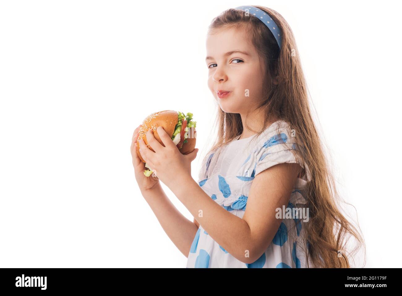 Petite fille mangeant un gros hamburger. Enfant regardant un gros sandwich sain, studio isolé sur fond blanc. Banque D'Images