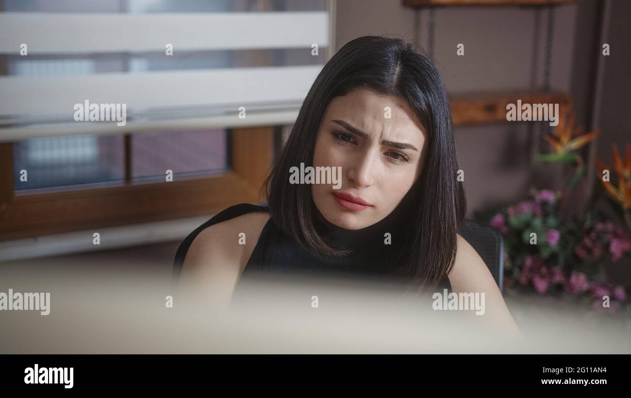 Femme sérieuse de cheveux noirs travaillant sur l'ordinateur à la maison. Concept de travail à domicile. Banque D'Images