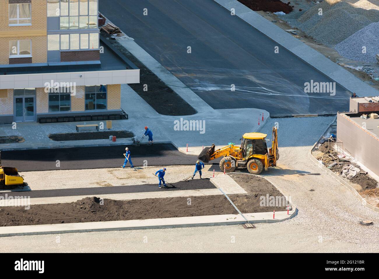 Les travailleurs de l'équipement spécial ponent de l'asphalte près d'une maison en construction. Chelyabinsk, Russie, 17 mai 2021 Banque D'Images