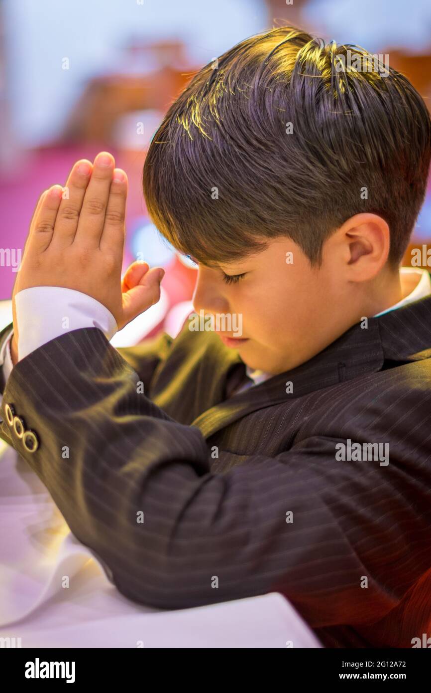 Enfant garçon priant dans une église catholique (pas de libération disponible) Banque D'Images