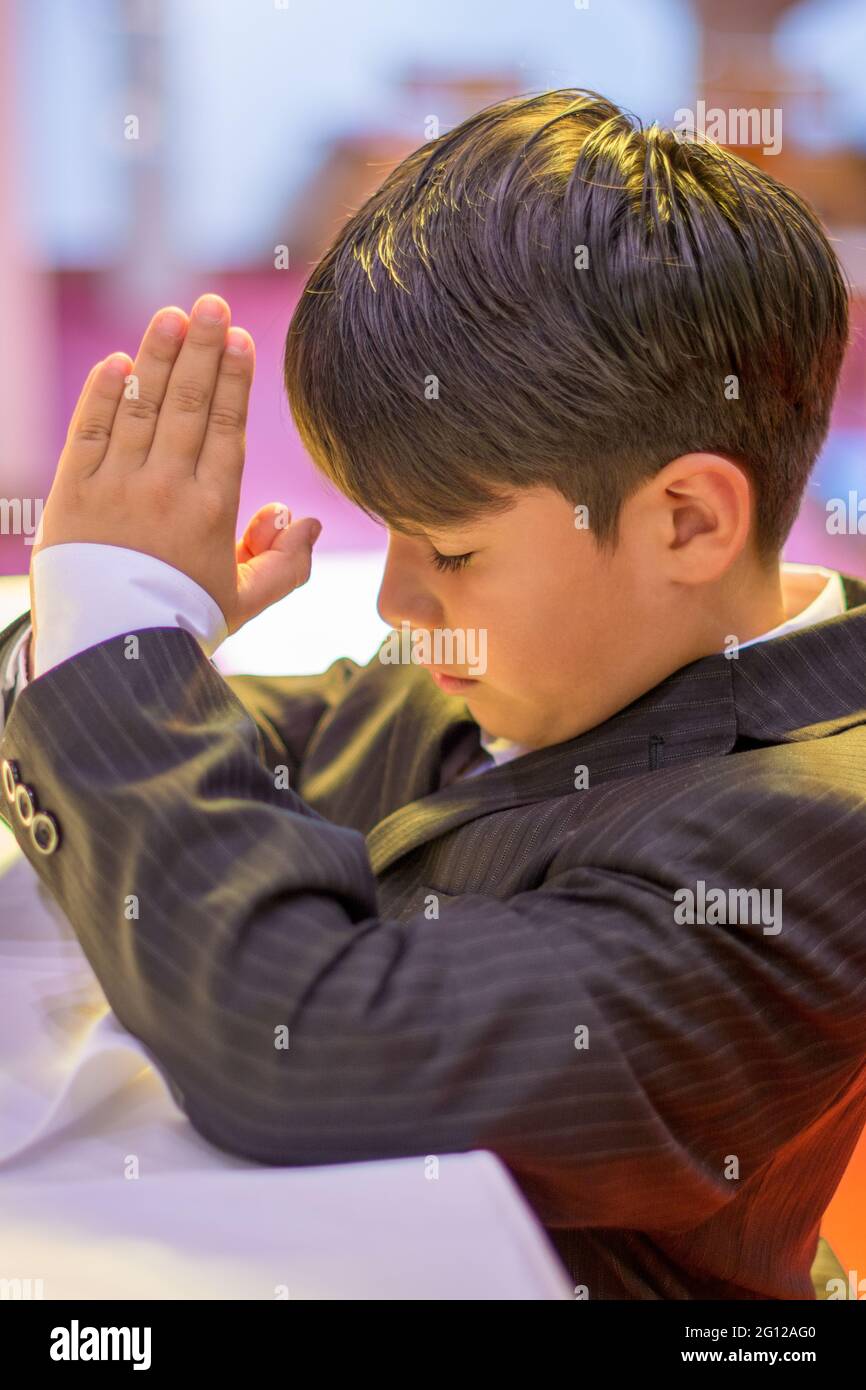 Enfant garçon priant dans une église catholique (pas de libération disponible) Banque D'Images