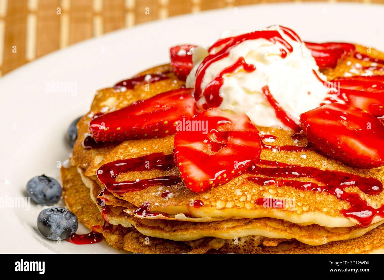 Vue colorée d'un délicieux petit déjeuner ou d'une crêpe de dessert avec de la crème glacée, des fraises, des myrtilles et du sirop. Banque D'Images