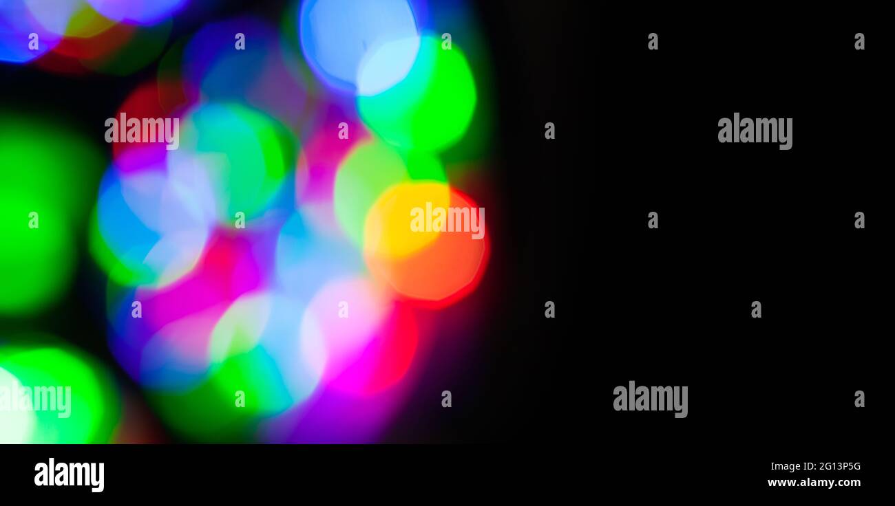 Lumières floues colorées effet bokeh dans l'obscurité. Texture de photo d'arrière-plan floue abstraite avec zone d'espace de copie noire vierge sur la vue de droite Banque D'Images