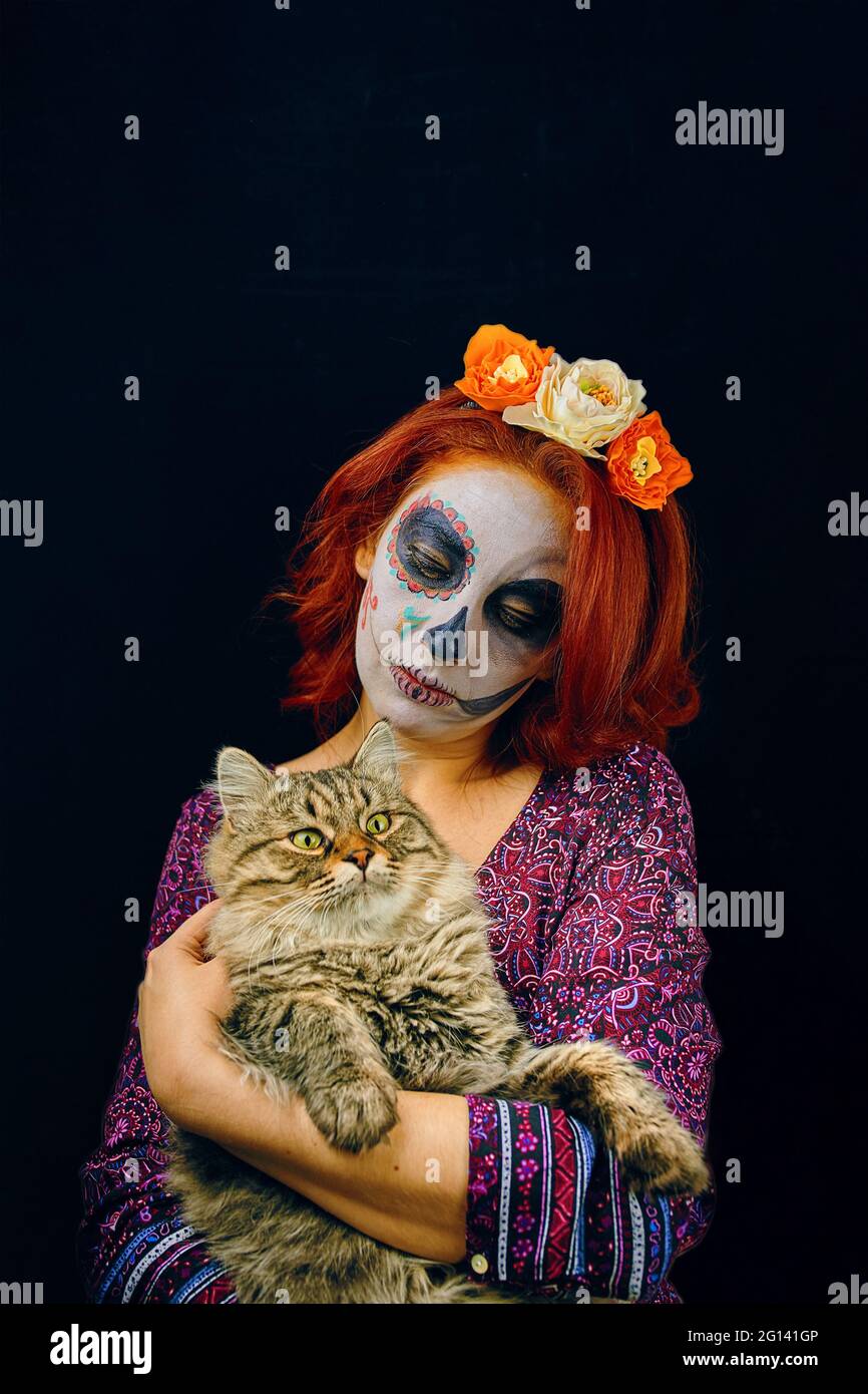 Une Jeune Femme Au Jour Du Visage Mort Masque Crane Art Femme Avec Maquillage De Crane Et Cheveux Rouges Avec Chat Dans Les Mains Sur Fond Sombre Photo Stock Alamy