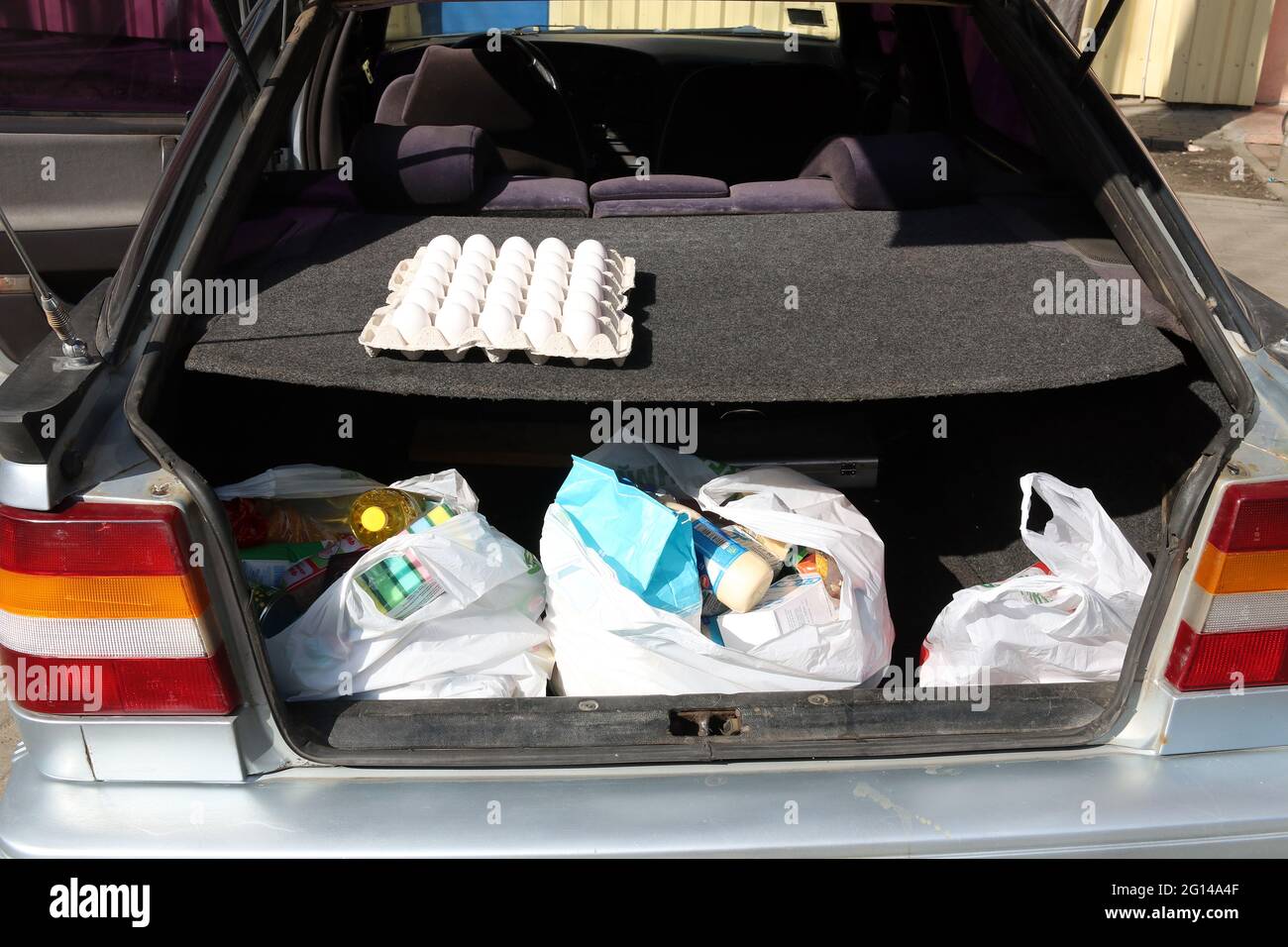 Sacs à provisions en plastique avec nourriture dans le coffre d'une voiture. Les gens achètent de la nourriture en grande quantité en raison du coronavirus. COVID-19. Banque D'Images