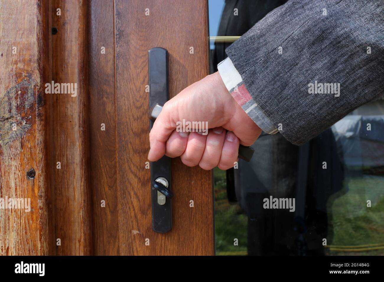 Homme d'affaires main ouvrant porte en bois à la maison Banque D'Images