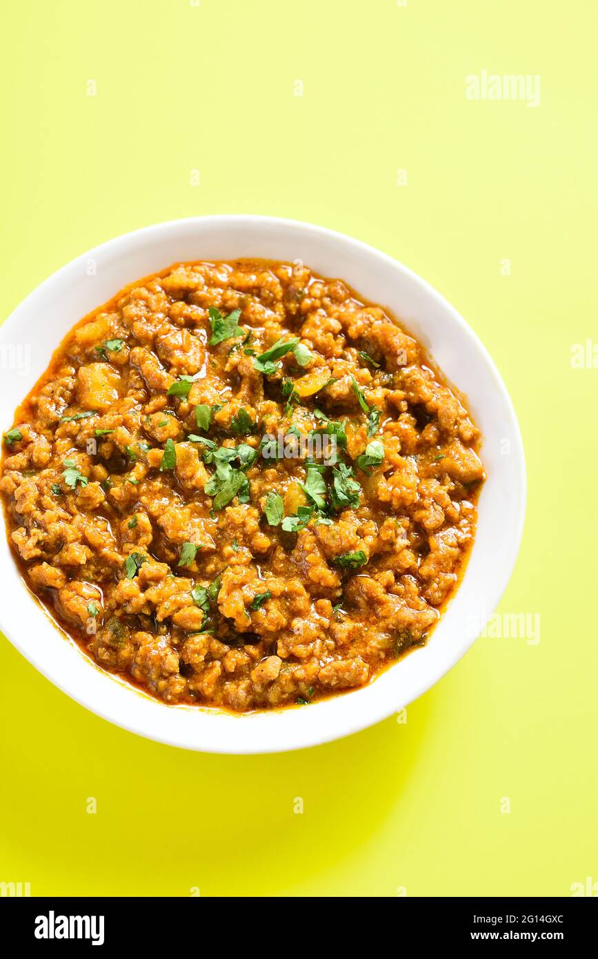 Vue rapprochée du curry de keema dans un bol sur fond jaune. Plat de style indien et pakistanais. Banque D'Images