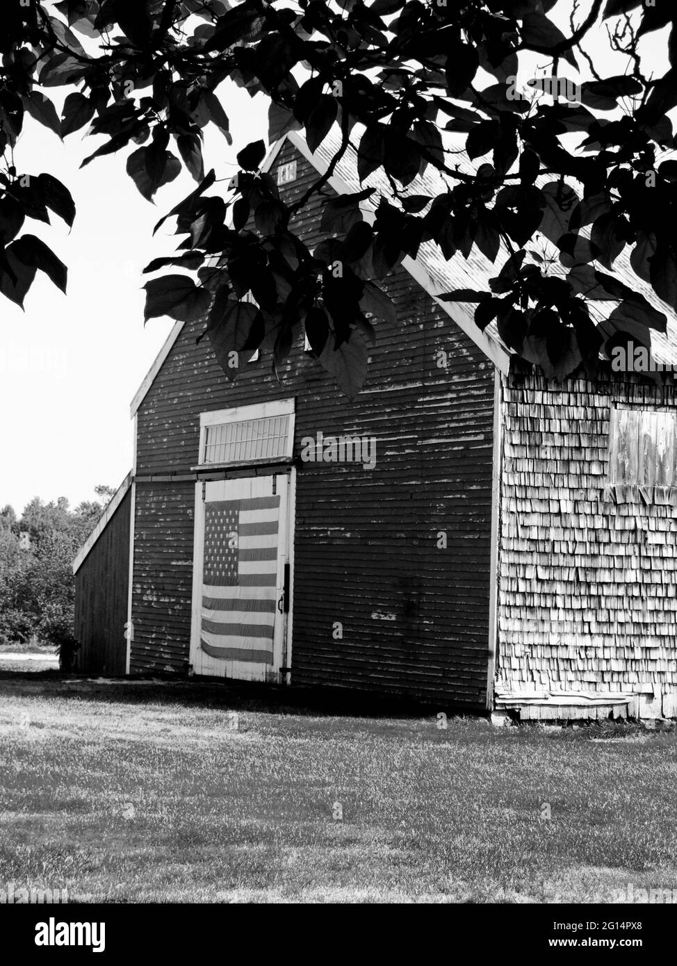 Photographie d'une ancienne grange avec un drapeau américain sur la porte de la grange, Nouvelle-Angleterre, Etats-Unis. Banque D'Images