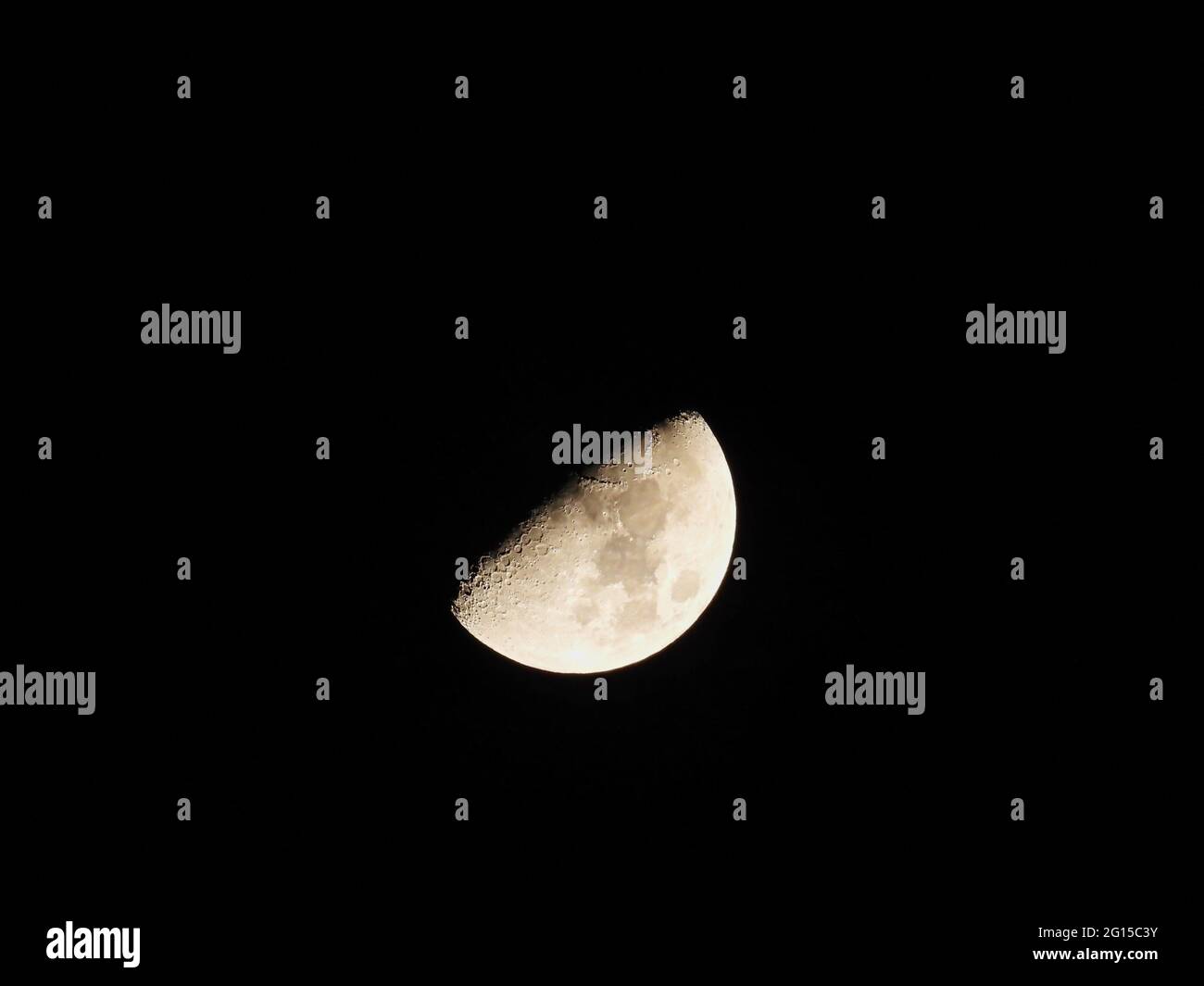 Demi-lune dans le ciel de nuit d'hiver : une demi-lune lumineuse avec des détails de cratères et des taches sombres et claires sur un ciel froid de nuit d'hiver Banque D'Images
