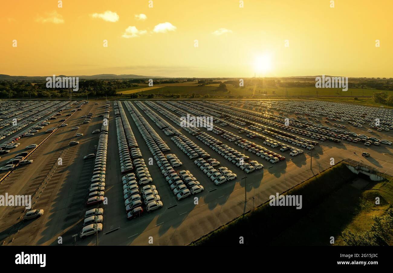 Vue aérienne de nouvelles voitures alignées dans le parking pour l'importation et l'exportation logistique d'affaires à la concession pour la vente, automobile et voiture par Banque D'Images