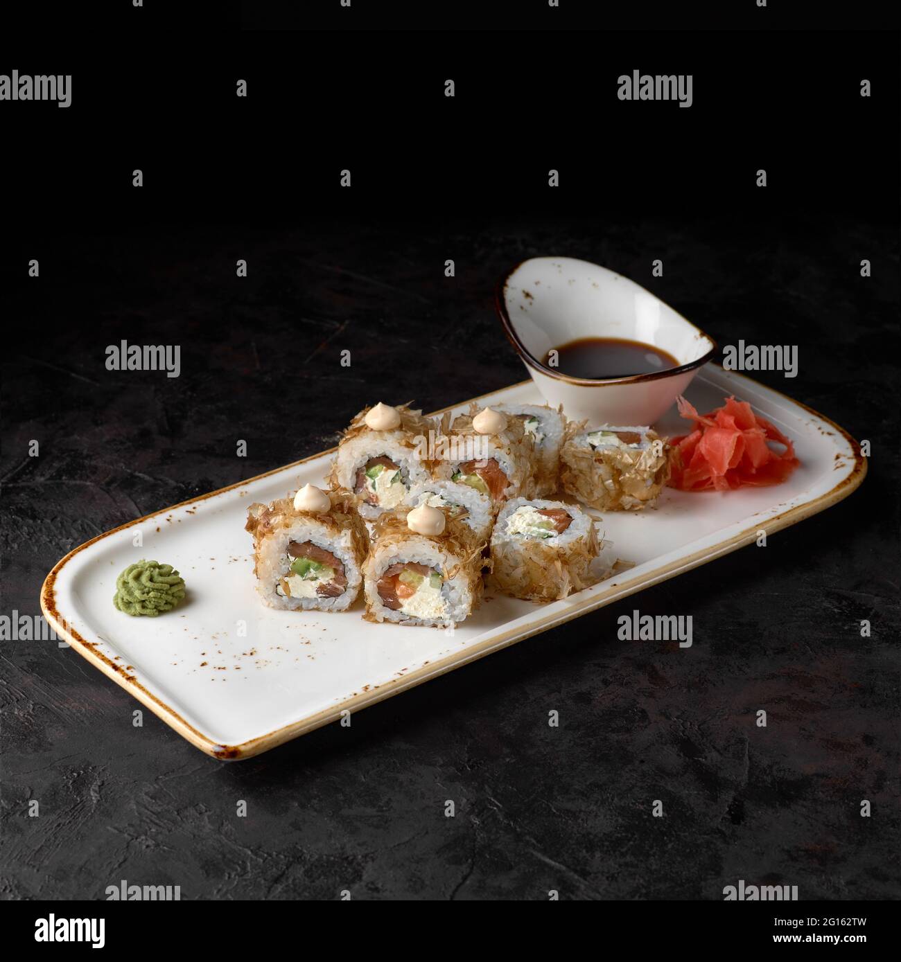 Sushi Bonito. Rouler avec du fromage, du concombre, du saumon et des flocons de thon sur fond noir texturé. Menu sushi. Cuisine japonaise. Banque D'Images