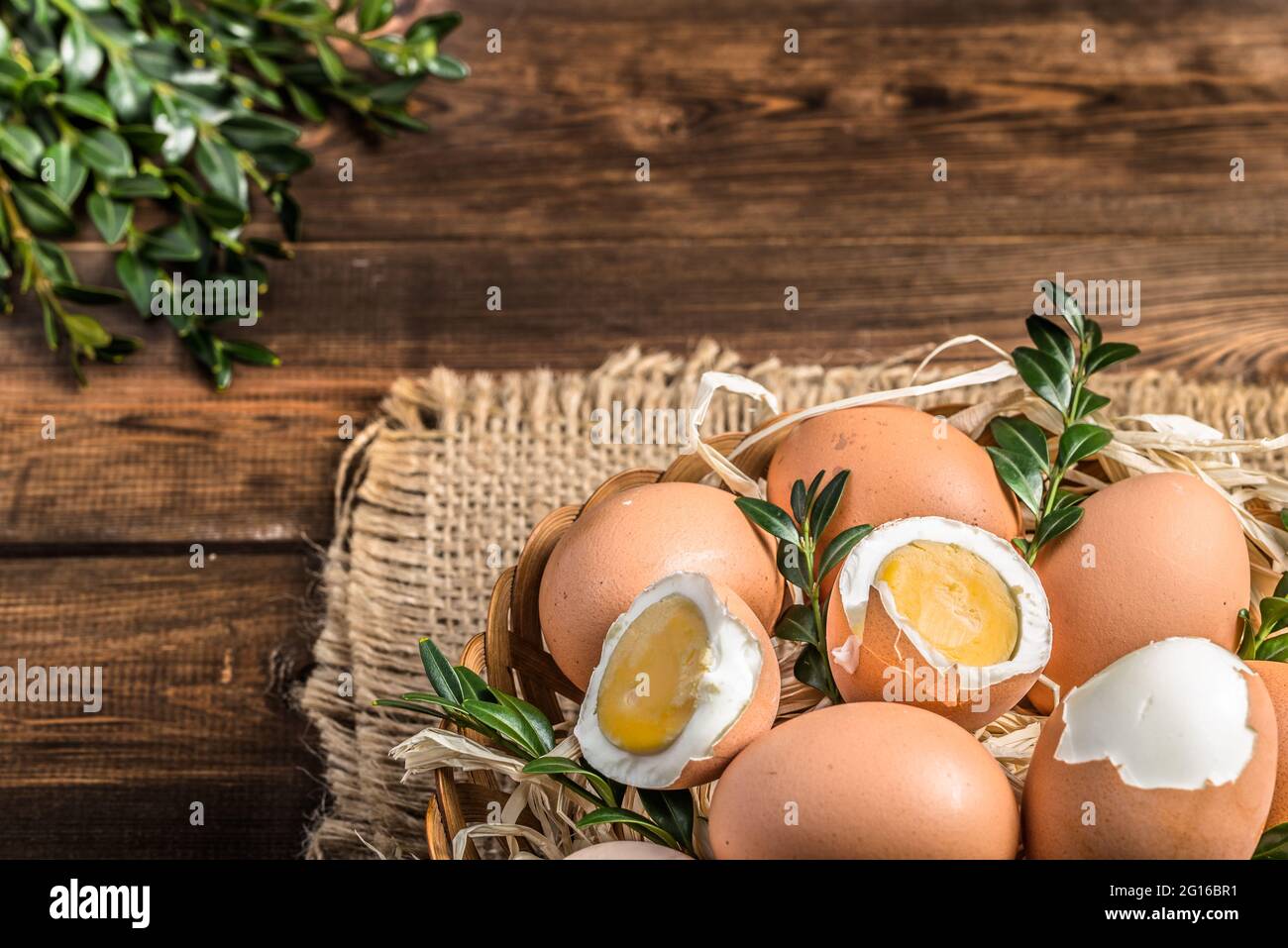 Œufs frais de ferme dans le panier et œuf dur, fond de pâques Banque D'Images