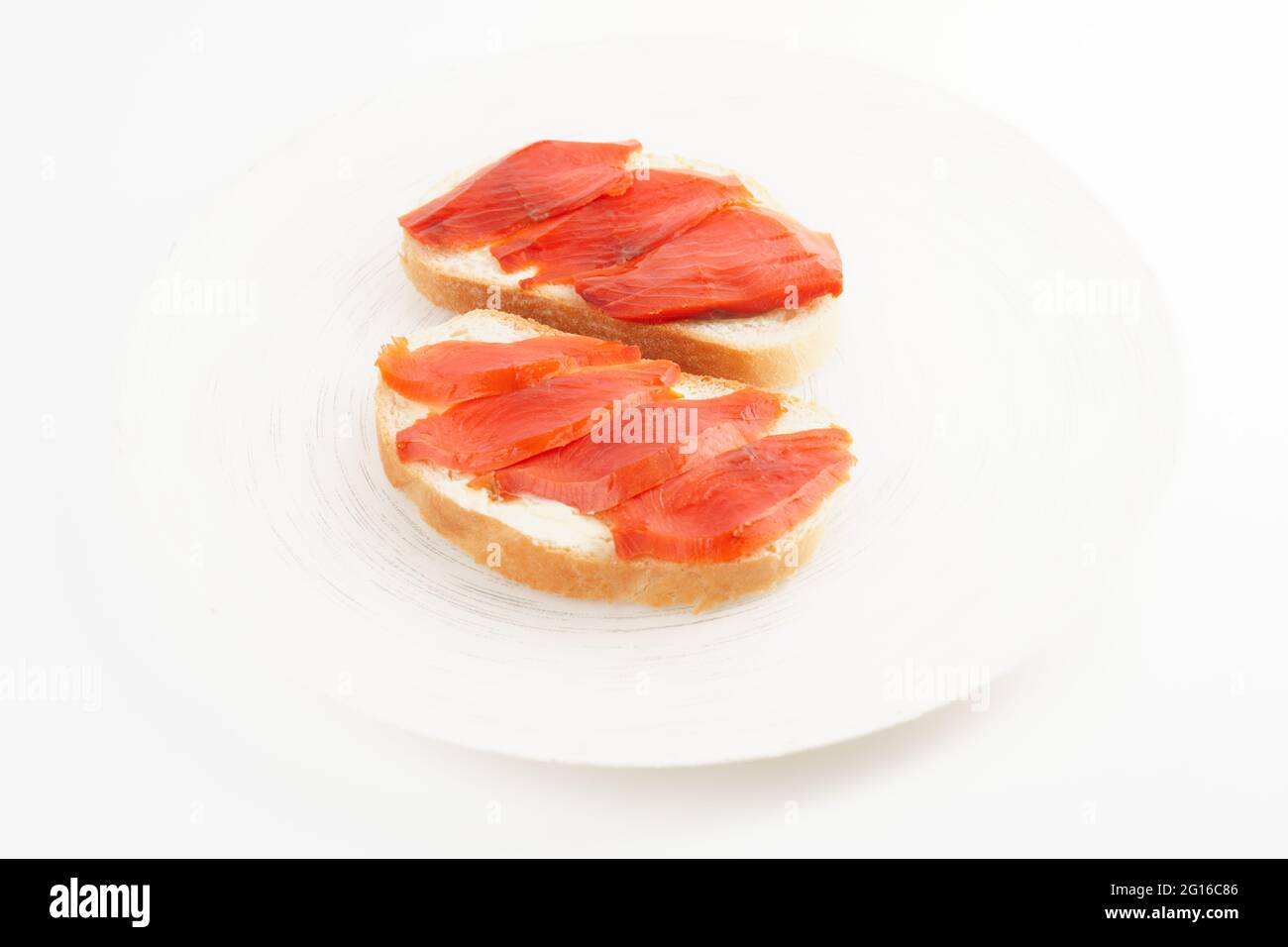 Deux sandwichs ouverts avec saumon fumé sur une assiette blanche Banque D'Images