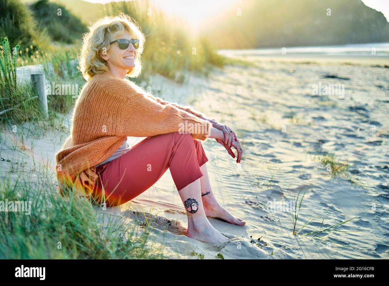 Jeune femme de race blanche, blonde et mûre, se détendant à l'extérieur sur une plage par temps ensoleillé. Banque D'Images