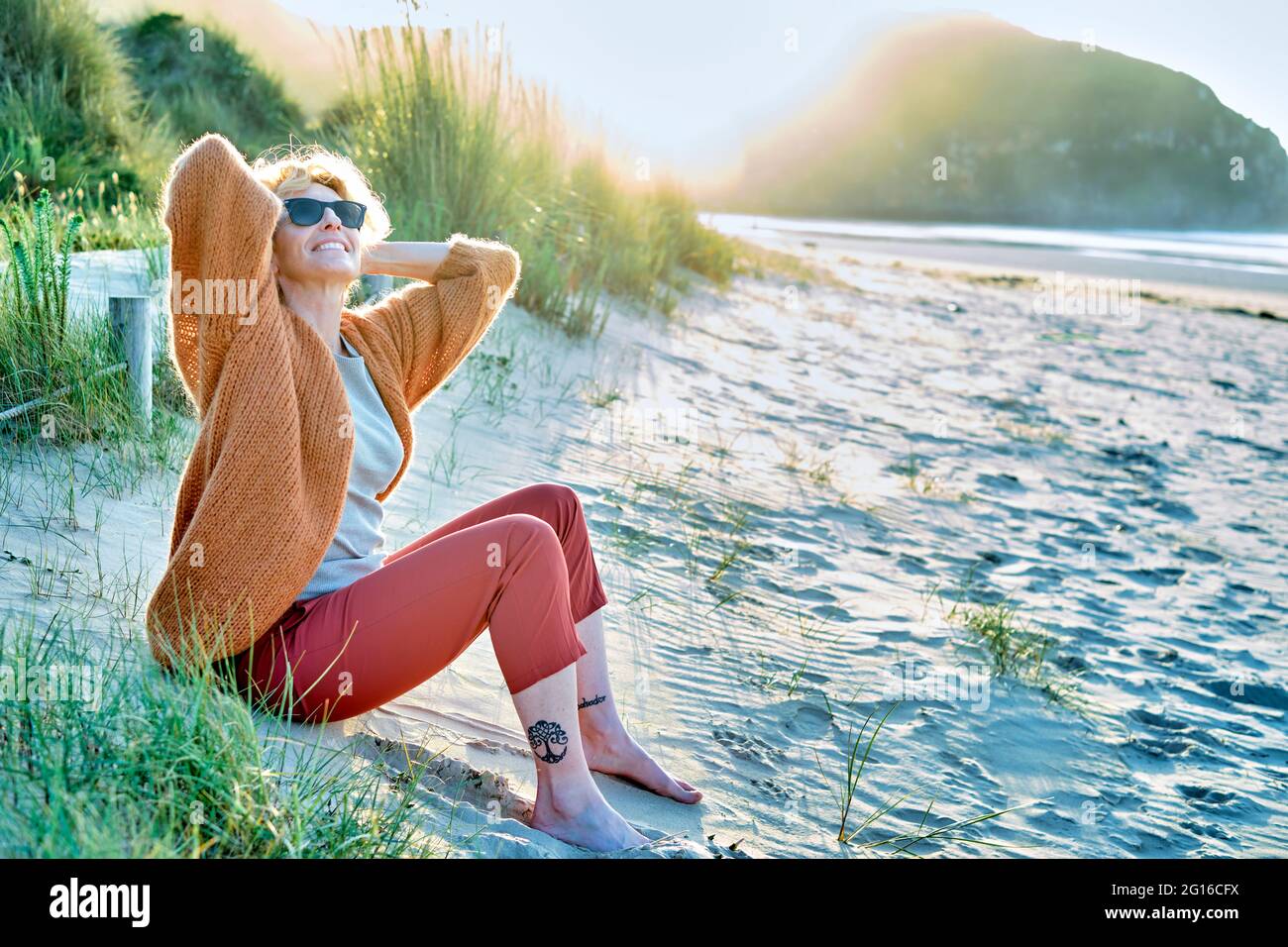 Jeune femme de race blanche, blonde et mûre, se détendant à l'extérieur sur une plage par temps ensoleillé. Banque D'Images