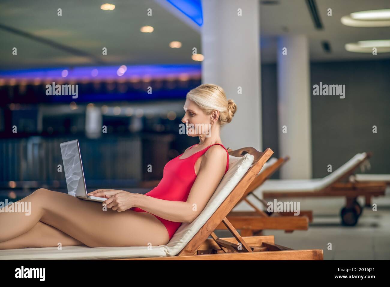 Femme blonde dans un costume de natation en roseau avec un ordinateur portable Banque D'Images