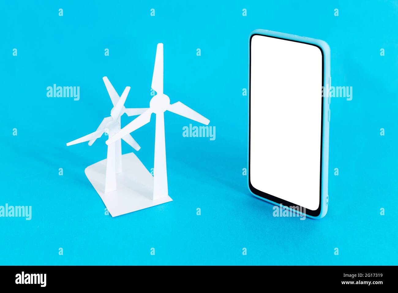 Petites icônes d'éoliennes et smartphone sur fond bleu clair Banque D'Images