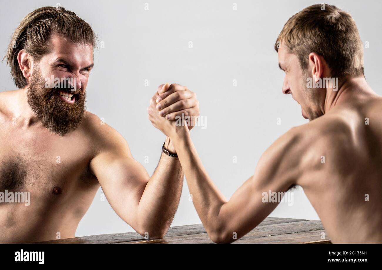 Homme barbu fortement musclé bras luttant un homme faible et puny. Bras luttant main mince, gros bras fort en studio. Deux mains d'homme ont classé le bras luttant Banque D'Images