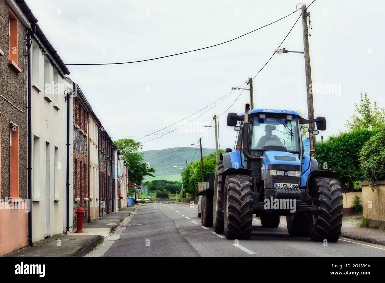 CORK, IRLANDE - JUIN 6 2012 : un tracteur New Holland bleu sur route dans la zone rurale, Dingle, Irlande Banque D'Images