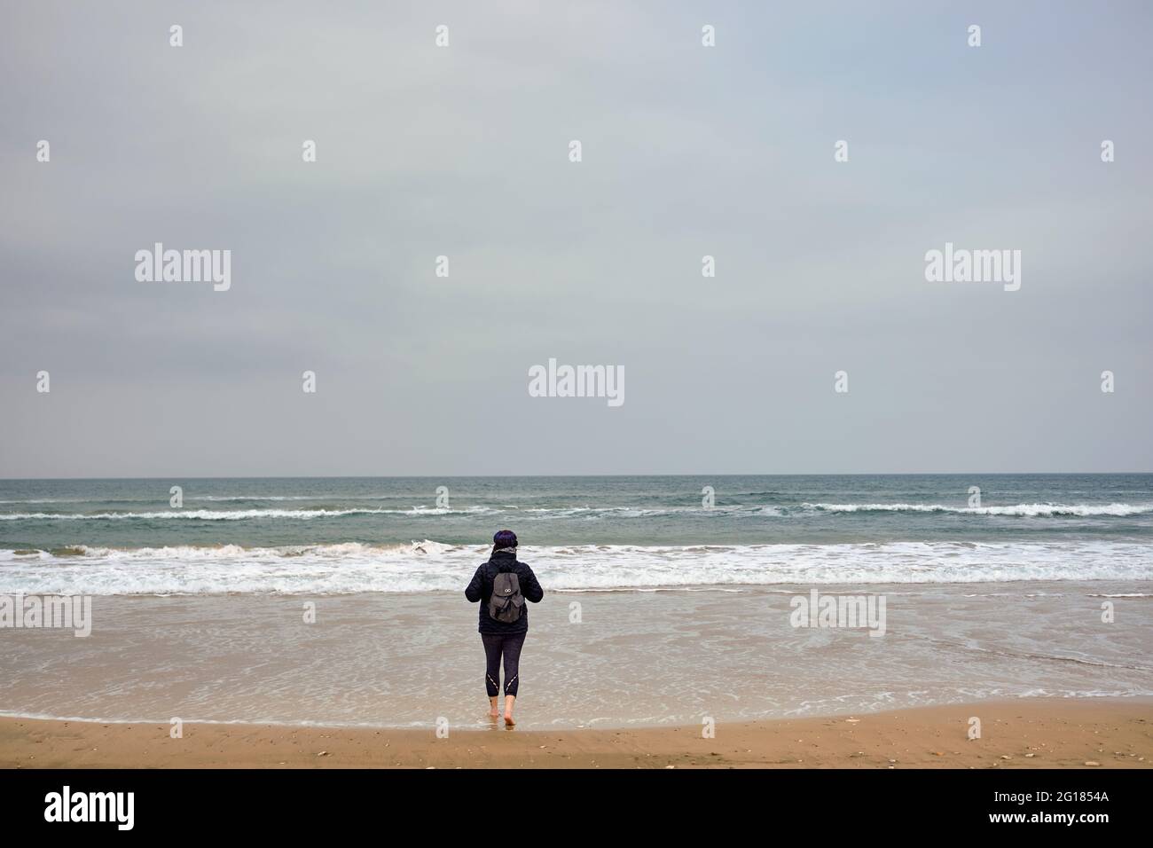 Femme marche dans l'océan Atlantique nord , l'Irlande du Nord, Royaume-Uni, 2018 Banque D'Images