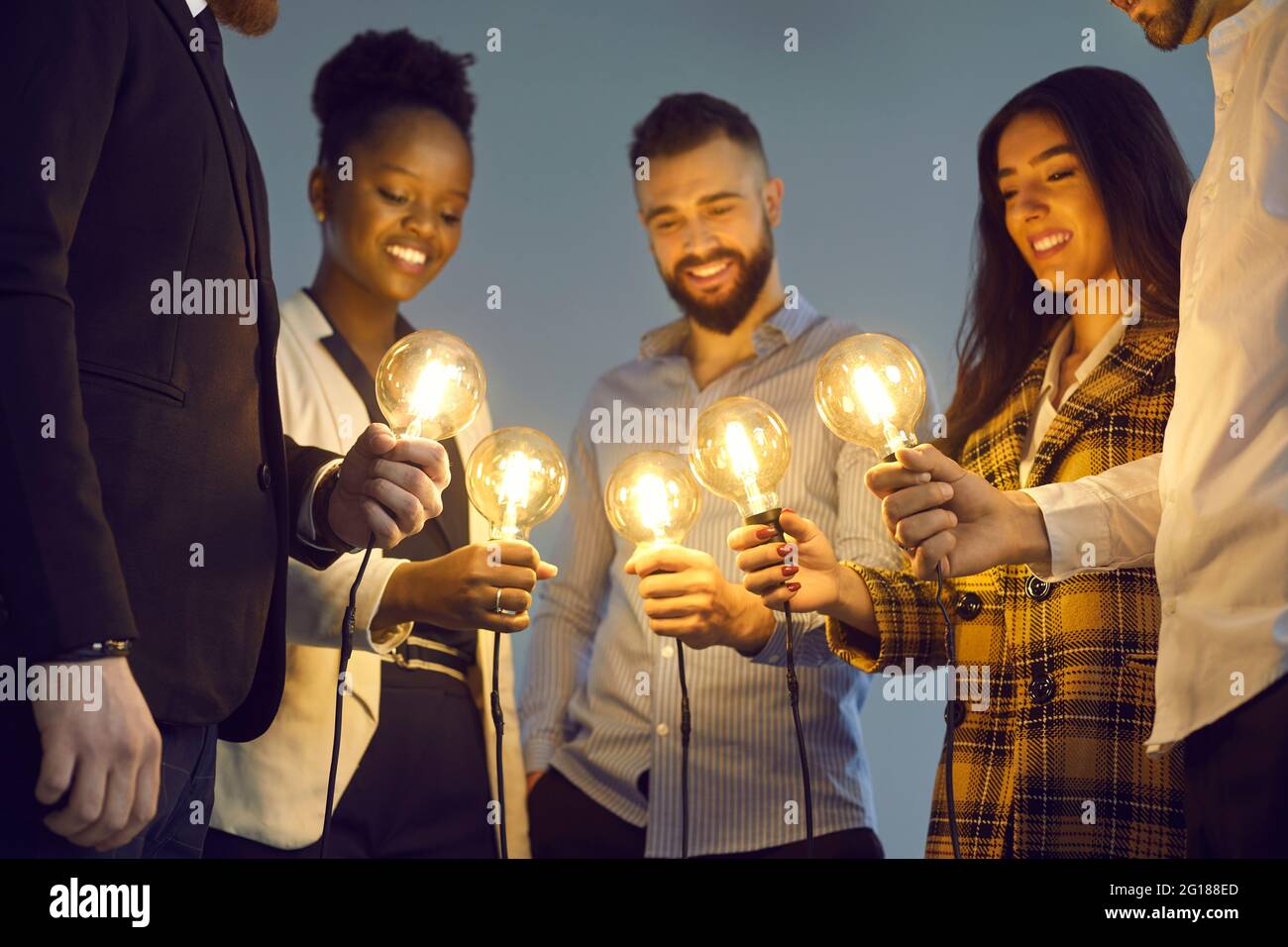 Une équipe d'affaires diversifiée se joint aux ampoules brillantes pour partager des idées créatives Banque D'Images