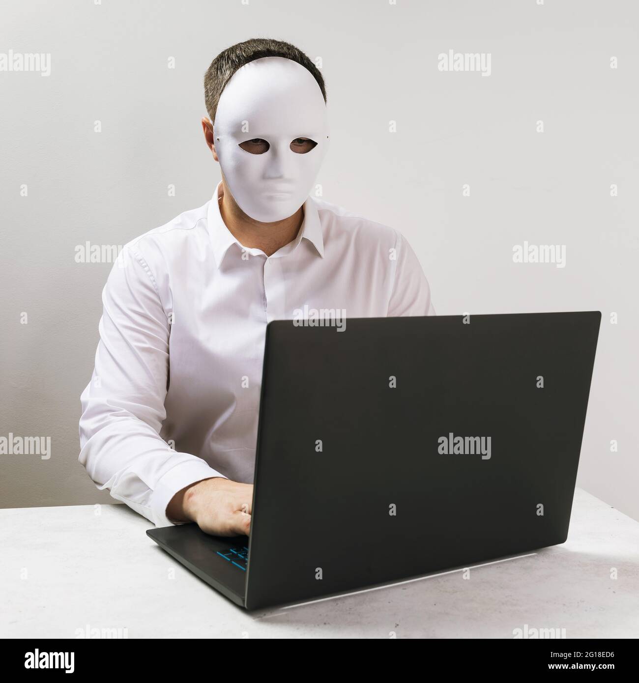 Un homme dans un masque travaille derrière un ordinateur portable, le concept de l'anonymat sur l'Internet. Banque D'Images
