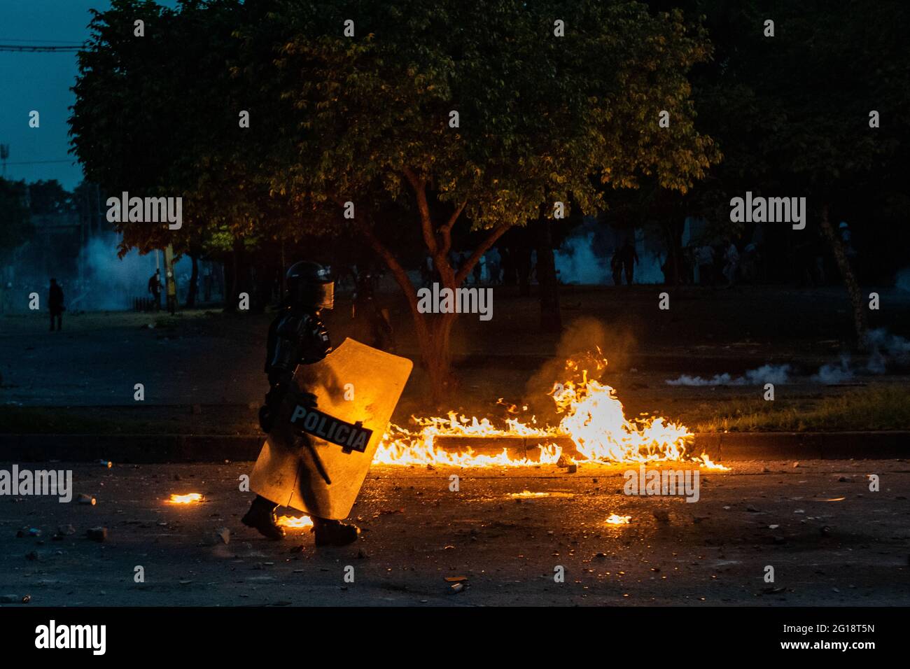 Un officier colombien de police anti-émeute (ESMAD) passe devant un incendie alors que des affrontements entre les manifestants et la police anti-émeute de Colombie (ESMAD) éclatent à Medellín, Colombie après plusieurs semaines de protestation anti-gouvernementale contre les réformes fiscales et sanitaires du Président Ivan Duque, les troubles et les abus de pouvoir qui ont fait au moins 70 morts selon les ONG le 4 juin 2021. Banque D'Images