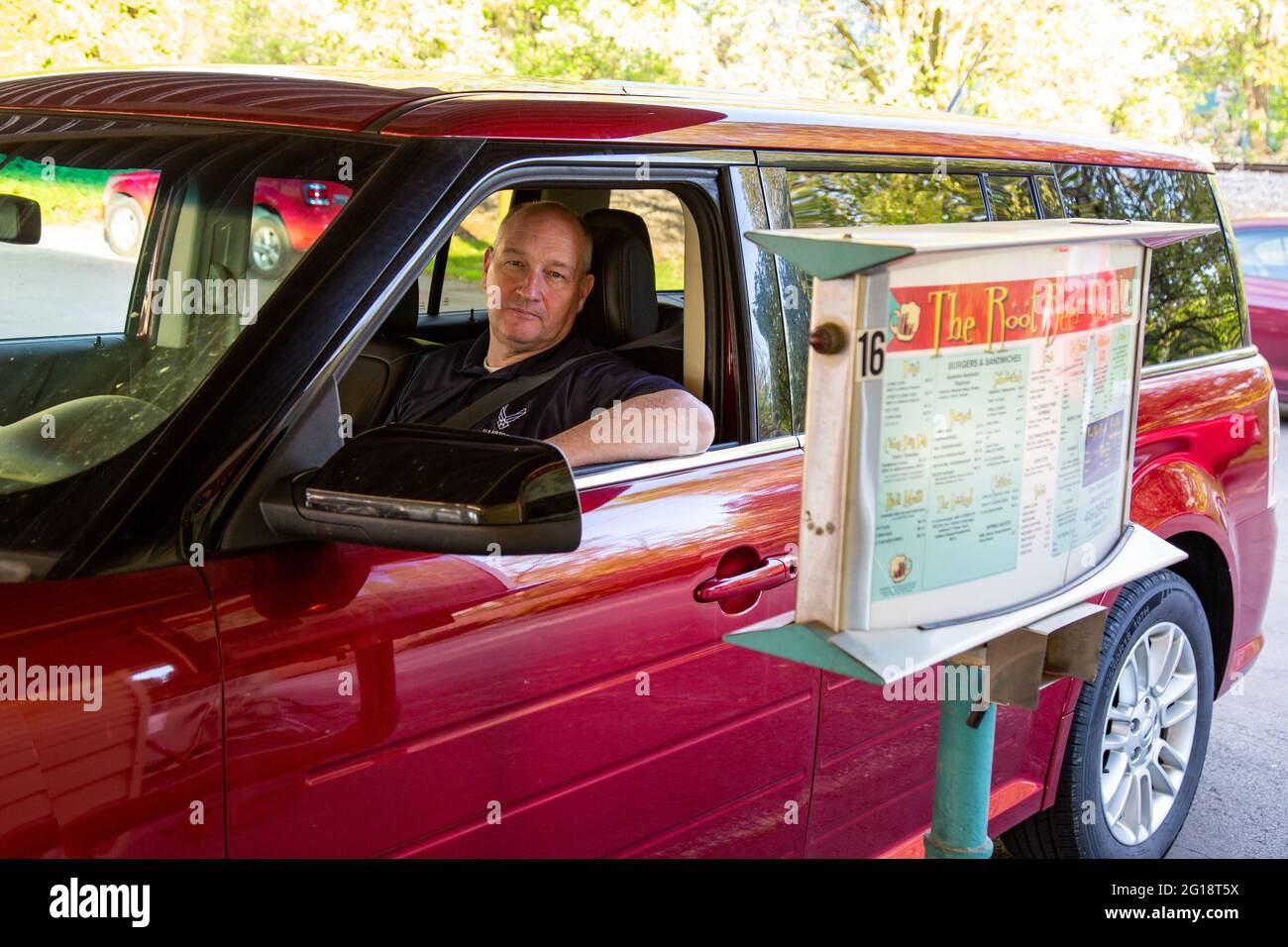 Un homme dans un rouge 2013 Ford Flex envisage son ordre au Root Beer Stand à Anvers, Ohio, Etats-Unis. Banque D'Images