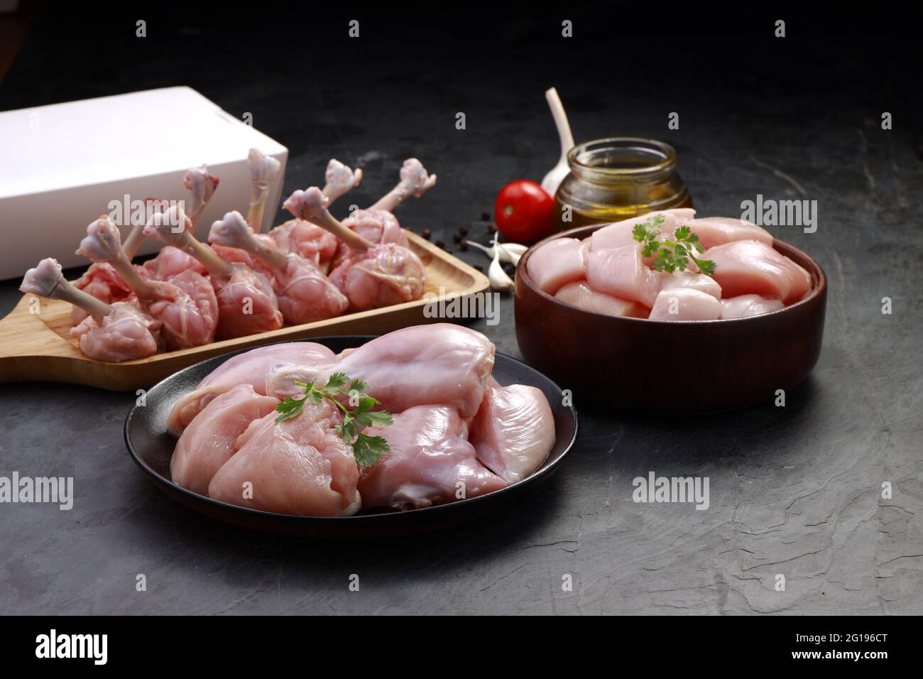 Combo de coupes de poulet cru, combinaison de coupes de poulet biriyani, coupes de poulet frite et lollipop de poulet disposés sur une planche en bois avec feuille de coriandre, gar Banque D'Images